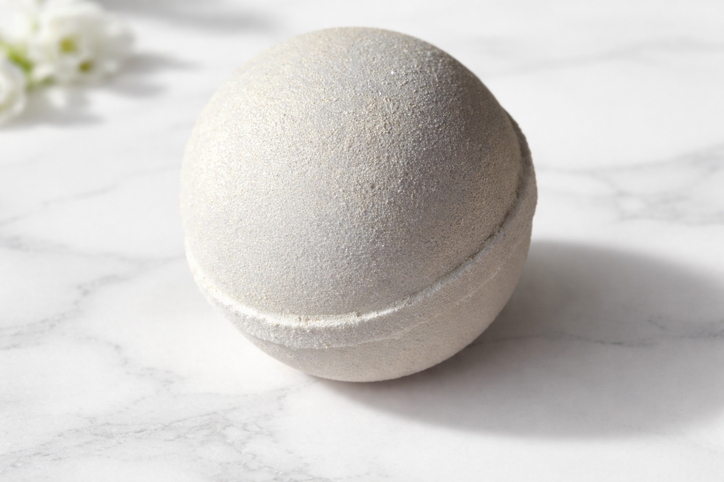 White bath bomb on a marble surface with a soft focus background