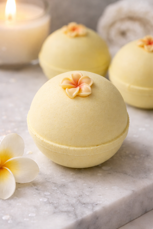 Yellow bath bombs with floral decorations on a marble surface with candles in the background