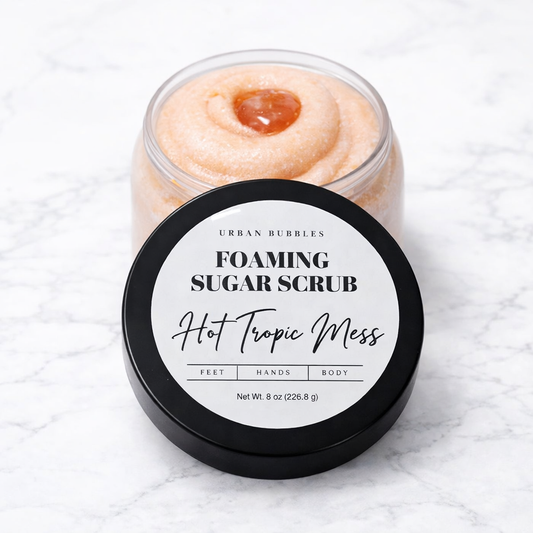 Jar of foaming sugar scrub labeled 'Hot Tropic Mess' on a textured white background