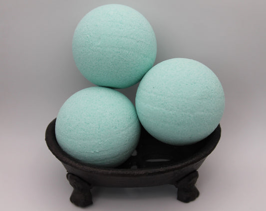 Three light blue bath bombs on a dark stand against a gray background