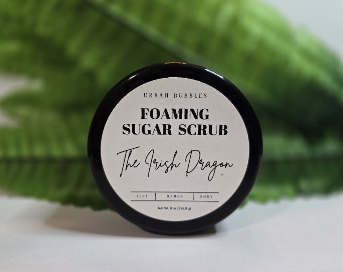 Foaming sugar scrub container labeled 'The Irish Dragon' with a green towel in the background.