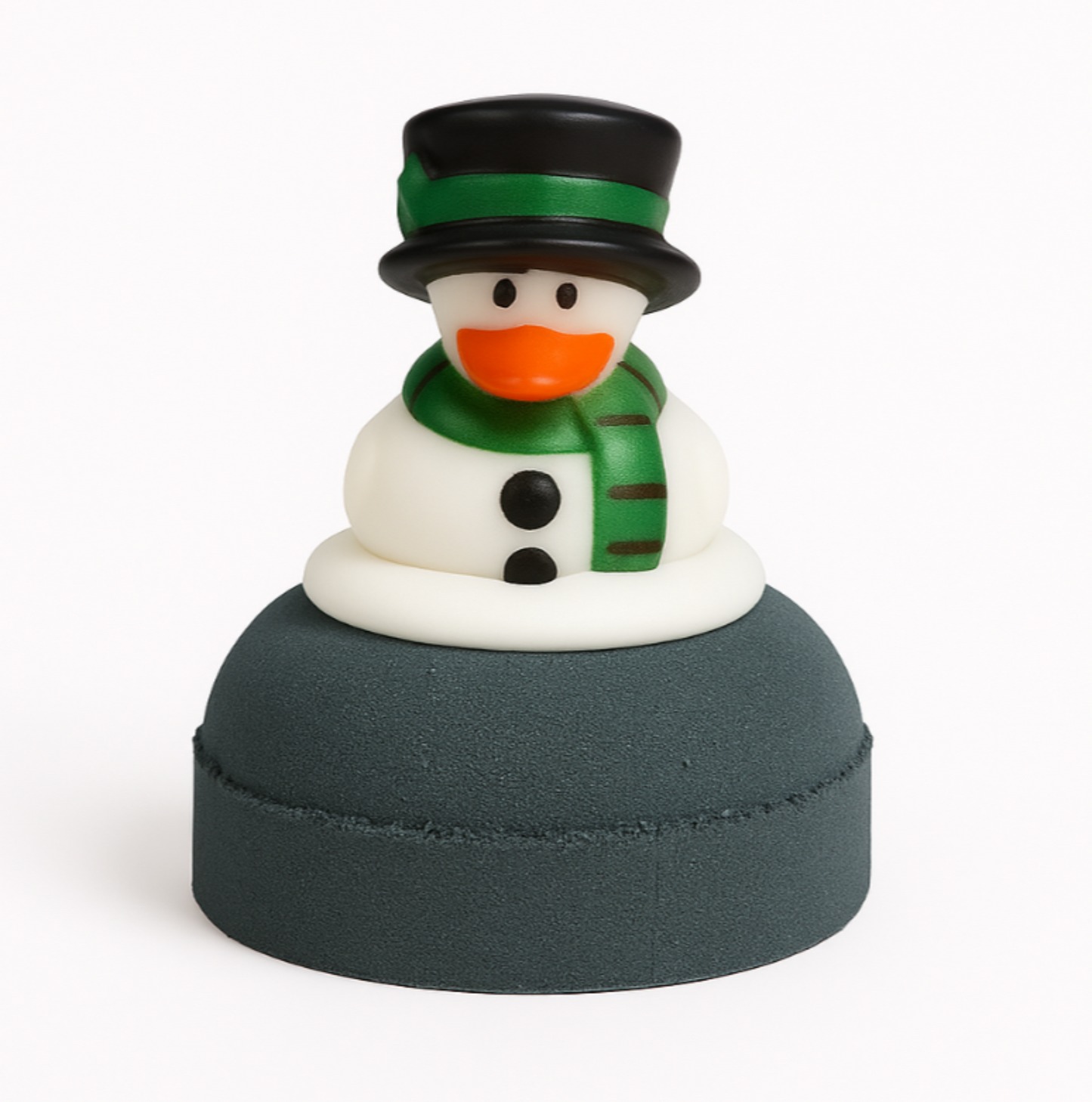Snowman duck with a green hat and scarf on top of a dark grey bath bomb on a white background