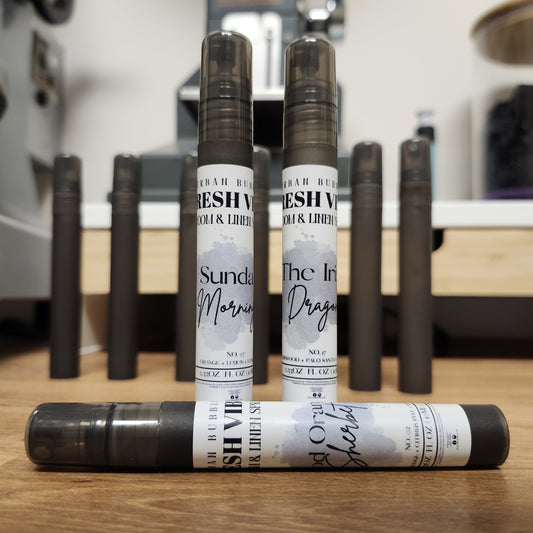 Three travel room and linen spray bottles with visible labels on a wooden surface