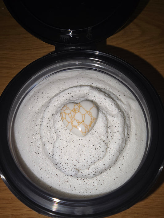 Close-up of a black container with a white, fluffy vanilla sugar scrub inside.
